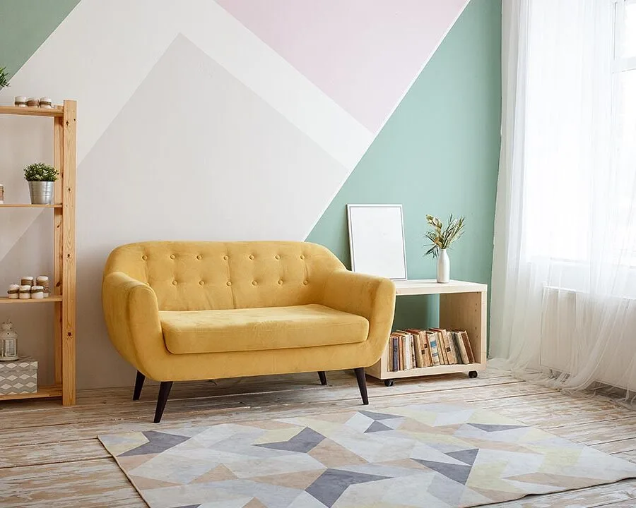Sarı koltuk ve geometrik desenli halı ile dekore edilmiş modern ve ferah oturma odası görünümü.