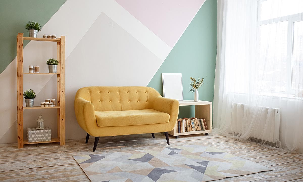 Sarı koltuk ve geometrik desenli halı ile dekore edilmiş modern ve ferah oturma odası görünümü.